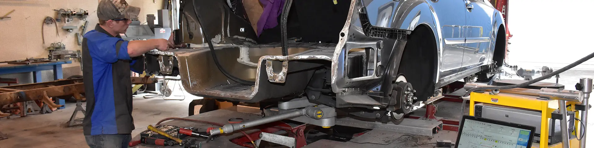 Auto technician working on a sliver metal frame of a car.